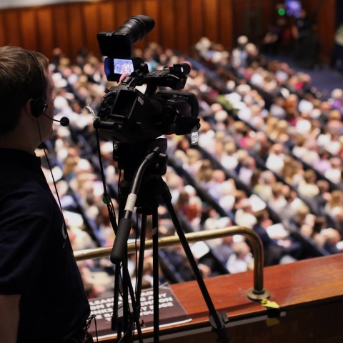 Person filming graduation ceremonies from balcony