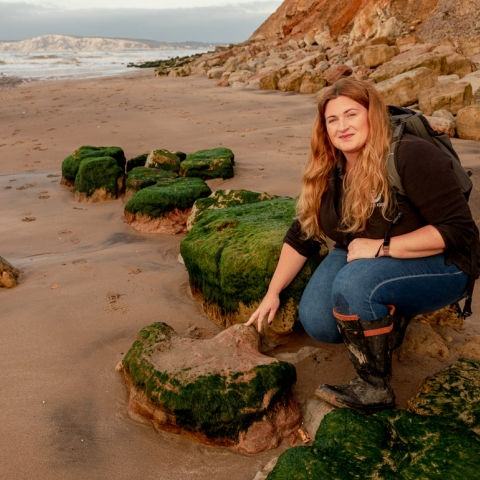 Megan crouched down touching a rock on the Isle of Wight