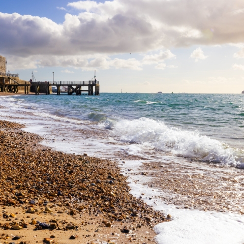Person walking along the shore of a Portsmouth beach