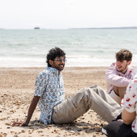 three students sat at the beach 