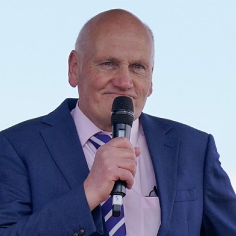 Eric Coleborn wearing blue suit holding microphone