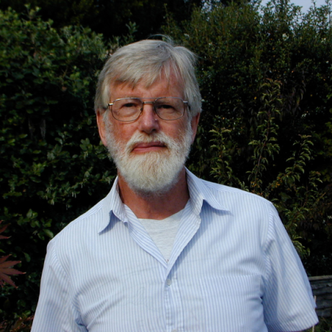 Ghillean Prance wearing glasses and shirt smiling to camera with tree backdrop