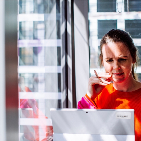 Student studying on laptop wearing orange jumper