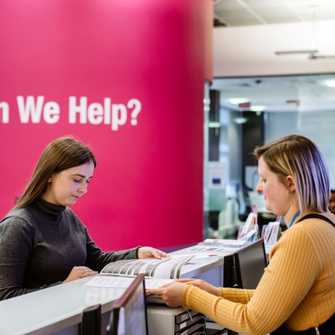 Careers adviser showing a student some resources at the front desk of the careers centre
