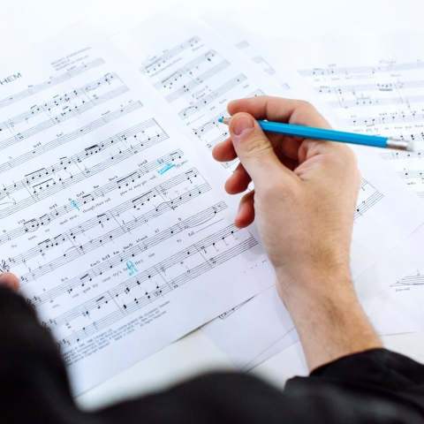 Person marking sheet music with light blue pencil