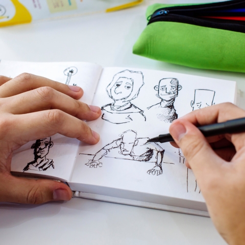 illustrator drawing in sketch book, close-up