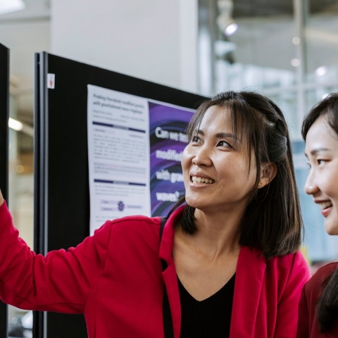 Photo of 2 attendees examining board.- Festival of Doctoral ResearchFOR GRADUATE SCHOOL USE ONLY