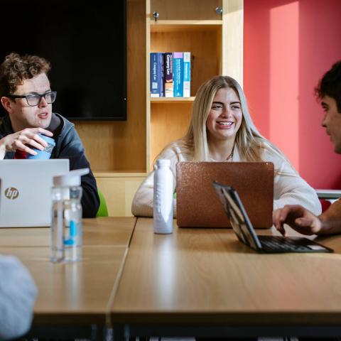 Students seated at a seminar with their laptops on a table