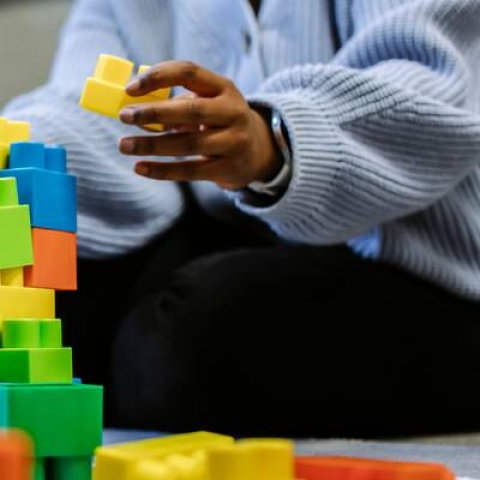 Someone building a tower with plastic toy blocks