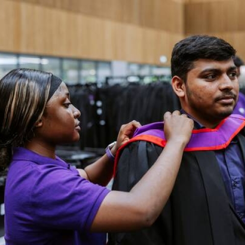 graduate putting on gown
