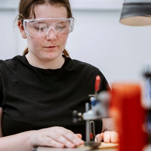 Student uses automatic Jigsaw on workstation to cut out component for model inside Technology Facilities