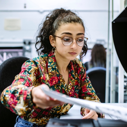 Female University of Portsmouth student feeding paper into a printer