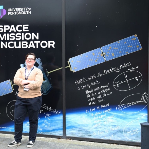 Dr Lucinda King standing in front of the sign for the Space Mission Incubator service