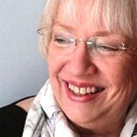 Picture of Maggie Winchcombe smiling to camera wearing glasses