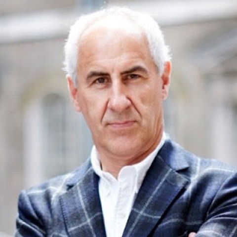 Headshot of Simon Ward looking to camera in suit with arms crossed