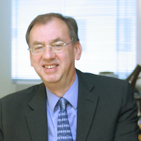 Stuart Iles sitting at desk and smiling at camera