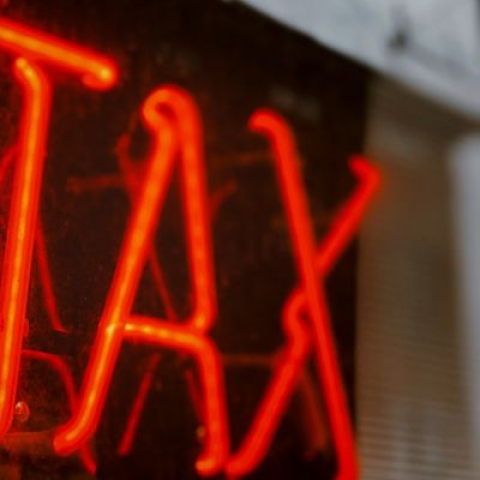 Red neon sign that reads TAX