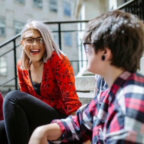 Students sitting on steps outside and laughing