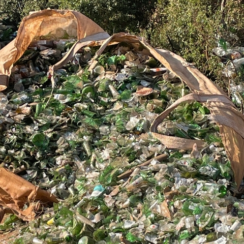 Large industrial size waste bag containing bottles of various shapes, sizes and colours, collected for recycling