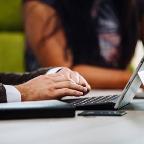 Hands hovering over a laptop