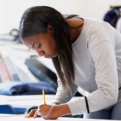 Woman standing over a table writing