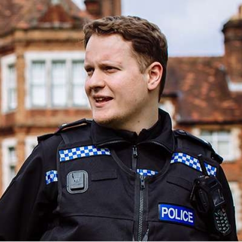 Police officer in uniform in front of criminology building