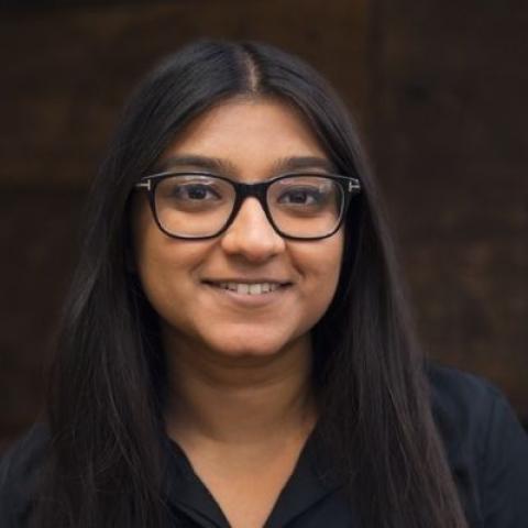 A woman with glasses, smiling