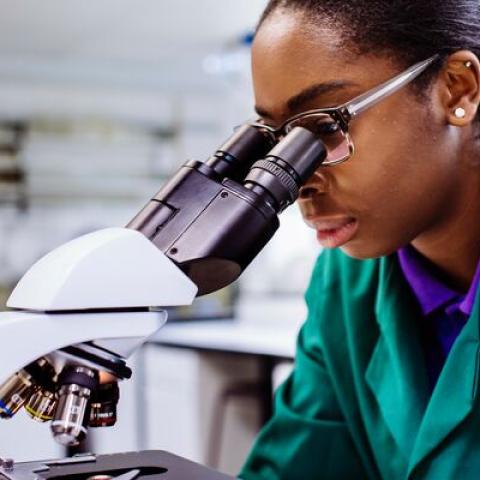 researcher looking down microscope