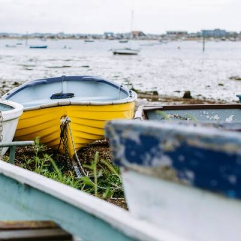 a group of colourful rowing boats sitting on the shore with the sea in the background