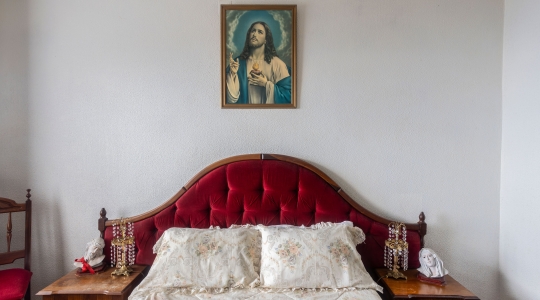 photo of a bed with a photo of jesus behind it on the wall