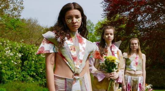 3 students wearing floral fashion garments outside in a flowery area
