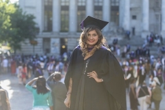 A female student smiling wearing black graduation robes in front of the Portsmouth Guildhall