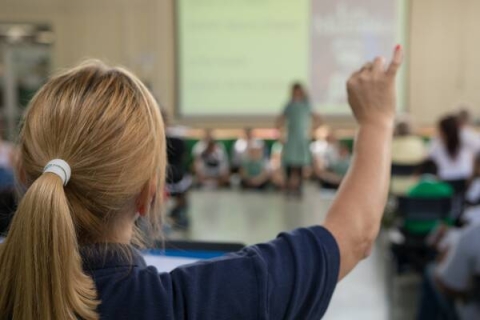 Teacher in classroom raising her hand