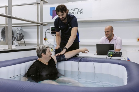 A study participant in a hot tub having her blood pressure checked 