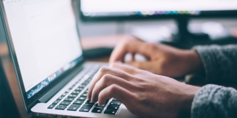 Hands typing on a laptop