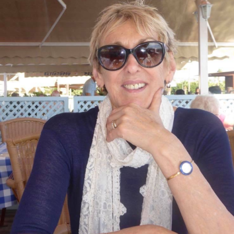 Christine King wearing sunglasses and smiling to camera