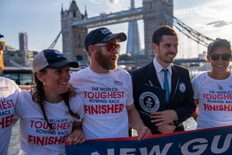 Two rowers and a Guinness World Record adjudicator in front of Tower Bridge, London,