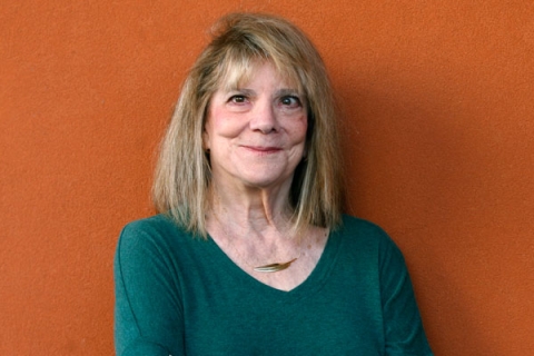 Headshot of Elizabeth Loftus wearing green jumper with necklace smiling to camera