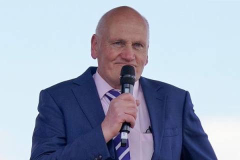 Eric Coleborn wearing blue suit holding microphone