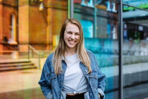 Student wearing blue jean jacket and smiling.