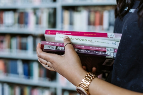 Close up of hands holding a pile of books