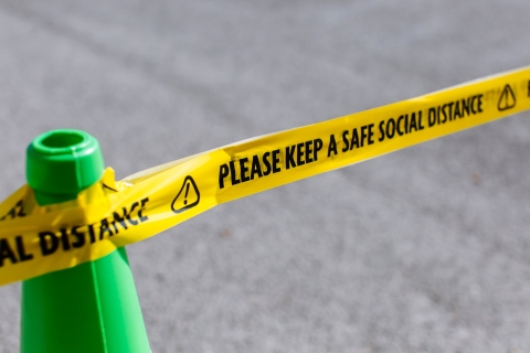 a green cone with tape warning of social distance