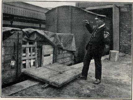 Image of a railway work on a station platform next to a goods crate with its side open and lying on the platform