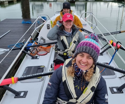 Three female rowers on their rowing boat ready to leave the harbour