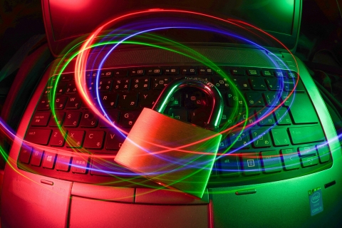 Image of a laptop computer keyboard with some swirls of light floating above and in the centre of that is a metal padlock