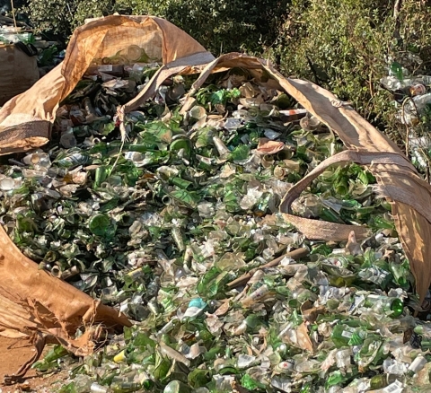 Large industrial size waste bag containing bottles of various shapes, sizes and colours, collected for recycling