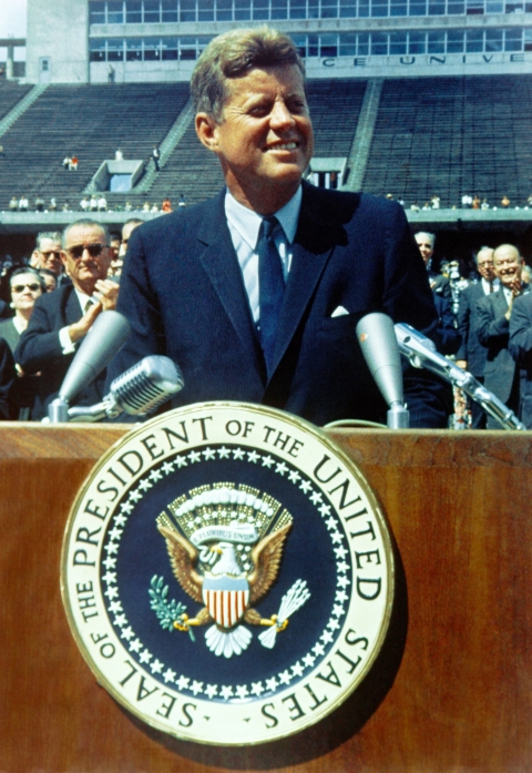 JFK standing on stage in front of podium - Photo by History in HD on Unsplash