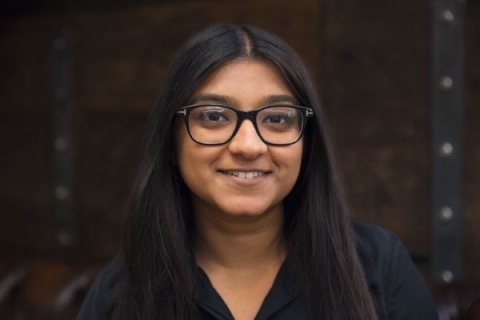 A woman with glasses, smiling