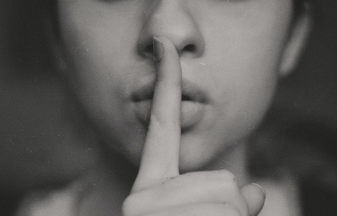 Person holding hush sign with finger over mouth - Photo by Kristina Flour on Unsplash