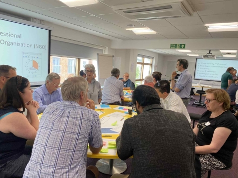 Several individuals seated at a table in a room, participating in a collaborative discussion